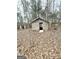A rustic wooden shed surrounded by trees and fallen leaves at 3210 Rogers Rd, Mcdonough, GA 30252
