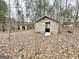 A rustic wooden shed surrounded by trees and fallen leaves at 3210 Rogers Rd, Mcdonough, GA 30252