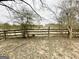 View of the lot featuring a rustic wooden fence and surrounding trees and foliage at 3210 Rogers Rd, Mcdonough, GA 30252
