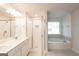 Bright bathroom featuring a double vanity, glass enclosed shower, and a soaking tub under a window at 4853 Walkers Green, Mableton, GA 30126