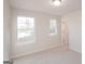 Bright bedroom featuring neutral walls, carpet, two windows providing natural light, and an open door at 4853 Walkers Green, Mableton, GA 30126