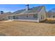 A view of backyard with a patio, and a home with gray siding, a chimney, and several windows at 227 Lantana Dr, Locust Grove, GA 30248