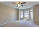 Bright bedroom featuring a ceiling fan, carpet flooring, and three large windows at 227 Lantana Dr, Locust Grove, GA 30248