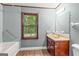 Bathroom with traditional wood vanity, mirror, and a view from the window overlooking the backyard at 105 Oak Leaf Ct, Fayetteville, GA 30214