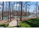 Scenic view of lake from backyard, featuring a wooden walkway, trees, and lush greenery at 4185 Etcetera Ln, Cumming, GA 30041