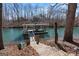 View of the covered boat dock with lift, stairs, and canoe access on a wooded lot with lake access at 4185 Etcetera Ln, Cumming, GA 30041