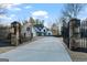 Gated entrance to a white two-story home with black trim and manicured landscaping on a sunny day at 4185 Etcetera Ln, Cumming, GA 30041