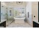 Elegant bathroom featuring marble tiles, a soaking tub, glass shower, and views of nature at 4185 Etcetera Ln, Cumming, GA 30041