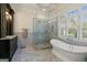 Bright bathroom boasting a soaking tub, glass shower, marble tiling, and black vanity cabinets at 4185 Etcetera Ln, Cumming, GA 30041