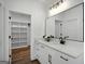 Modern bathroom features a white vanity with black hardware and a large mirror, complemented by wood-look tile and a walk-in closet at 5167 Martin St, Covington, GA 30014