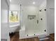 Bright bathroom featuring a glass-enclosed shower, soaking tub, window, and elegant tile work at 5167 Martin St, Covington, GA 30014
