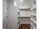 Walk-in closet provides organization with custom built-in shelving, hanging rods, and wood-look flooring at 5167 Martin St, Covington, GA 30014