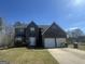 Charming two-story home featuring a stone facade, two-car garage, and manicured front lawn at 10988 Mansura Pl, Hampton, GA 30228
