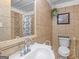 This bathroom features tan tiles, a white toilet, and a white sink with chrome fixtures at 1202 Coan Dr, Locust Grove, GA 30248