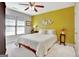 Bright bedroom with a white bedspread, yellow accent wall, and ceiling fan at 123 Fielding Rdg, Peachtree City, GA 30269