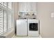 Functional laundry room features a washer, dryer, storage cabinets, and shuttered windows for natural light at 123 Fielding Rdg, Peachtree City, GA 30269