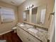 Bathroom with a double sink vanity featuring a granite countertop, framed mirrors, and wood flooring at 2430 Fern Valley Ct, East Point, GA 30344