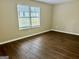 Neutral bedroom with hardwood flooring, base trim, and natural light with a large window at 890 Old Rocky Rd, Atlanta, GA 30349