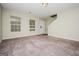 Spacious carpeted living room featuring a large window and staircase to the second floor at 415 Arthurs Ln, Covington, GA 30016