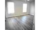 Bright bedroom featuring plank flooring, white trim, neutral walls, and two windows at 8053 Woodlake Dr, Riverdale, GA 30274