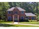 Charming two-story brick home with blue shutters, surrounded by lush greenery and mature trees, offers a welcoming ambiance at 230 Mapledale Trl, Sharpsburg, GA 30277
