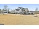 Expansive front yard showcases a modern farmhouse with a three-car garage and basketball hoop on a sunny day at 132 Platinum Rdg, Sharpsburg, GA 30277