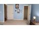 A bedroom with blue walls, two white doors, carpeted floors, and artwork on the walls at 35 Abelia Dr, Covington, GA 30014