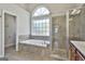 Bathroom featuring a soaking tub, glass enclosed shower, and a large window letting in natural light at 44 Willow Leaf Way, Sharpsburg, GA 30277