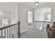 Upstairs hallway featuring carpet flooring, wood railing, and an open view of a bedroom at 44 Willow Leaf Way, Sharpsburg, GA 30277