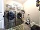 Modern laundry room featuring stainless steel washer and dryer with tiled floor at 34 Brittany Way, Palmetto, GA 30268