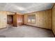 Bright bedroom showcasing wood-paneled walls, carpeted floor, closet, and natural light from a window at 5211 Old Monticello Se St, Covington, GA 30014