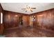 Living room with wood-paneled walls, tiled flooring, a ceiling fan, and multiple doorways at 5211 Old Monticello Se St, Covington, GA 30014