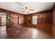 Living room with wood-paneled walls, tiled flooring, a ceiling fan, built-in shelves, and a doorway at 5211 Old Monticello Se St, Covington, GA 30014