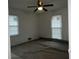 Bedroom with ceiling fan and two windows offering natural light with dark carpet flooring at 676 Bralorne Dr, Stone Mountain, GA 30087