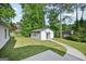 View of a backyard shed, a lush green lawn, a sidewalk, and trees at 2768 Southpark Sw Blvd, Conyers, GA 30094