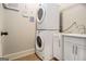 Compact laundry area with stacked washer and dryer, and white cabinets next to a sink at 6 Water Oak Dr, Sharpsburg, GA 30277