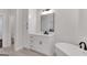 Bright bathroom featuring a bathtub, vanity with mirror, white cabinetry and modern fixtures at 118 Via Roma, Woodstock, GA 30188