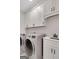 Well-lit laundry room with washer, dryer, white cabinets, and sleek sink at 118 Via Roma, Woodstock, GA 30188
