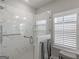 Modern bathroom with a glass shower featuring marble-look walls and a window with shutter blinds at 645 Timberbrook Dr, Sharpsburg, GA 30277