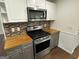 Kitchen featuring stainless stove and microwave, butcher block countertops and tile backsplash at 281 Timber Laurel Ln, Lawrenceville, GA 30043