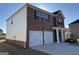 Side view of a charming two-story brick home featuring a two-car garage and white siding on one side at 1224 Hibiscus Way, Mcdonough, GA 30253