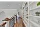 Upstairs hallway featuring hardwood floors, an arched ceiling, and custom built-in bookshelves at 2892 Darlington Run, Duluth, GA 30097