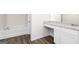 Bathroom featuring a white vanity with granite countertop and wood-look tile floors and a tub/shower combo at 909 Hesston Dr, Locust Grove, GA 30248