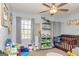 A cozy bedroom with a crib, toys, and a window view at 550 Stateline Rd, Bowdon, GA 30108