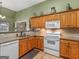 Traditional kitchen with wooden cabinetry, granite countertops, and white appliances at 925 Champions Way, Mcdonough, GA 30252