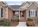 Inviting front porch with stone accents, a cozy bench, and decorative plants near the entrance at 172 Sam Solomon Rd, Locust Grove, GA 30248