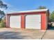 Red metal building with two white garage doors and a side entrance on a sunny day at 434 Lees Lake Rd, Fayetteville, GA 30214