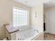 Well-lit bathroom featuring a large soaking tub, a decorative window, and neutral paint at 2110 Mcgarity Rd, Mcdonough, GA 30252