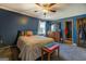Comfortable bedroom with a colorful bed, stained ceiling fan, and blue walls at 3579 Bill Gardner Pkwy, Locust Grove, GA 30248