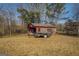 Exterior view of a rustic outbuilding with an attached trailer on a grassy lot at 3579 Bill Gardner Pkwy, Locust Grove, GA 30248